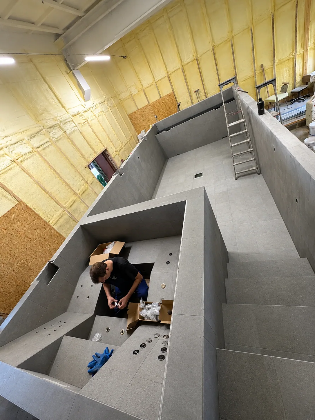 Technician fitting components inside a tiled pool at the workshop